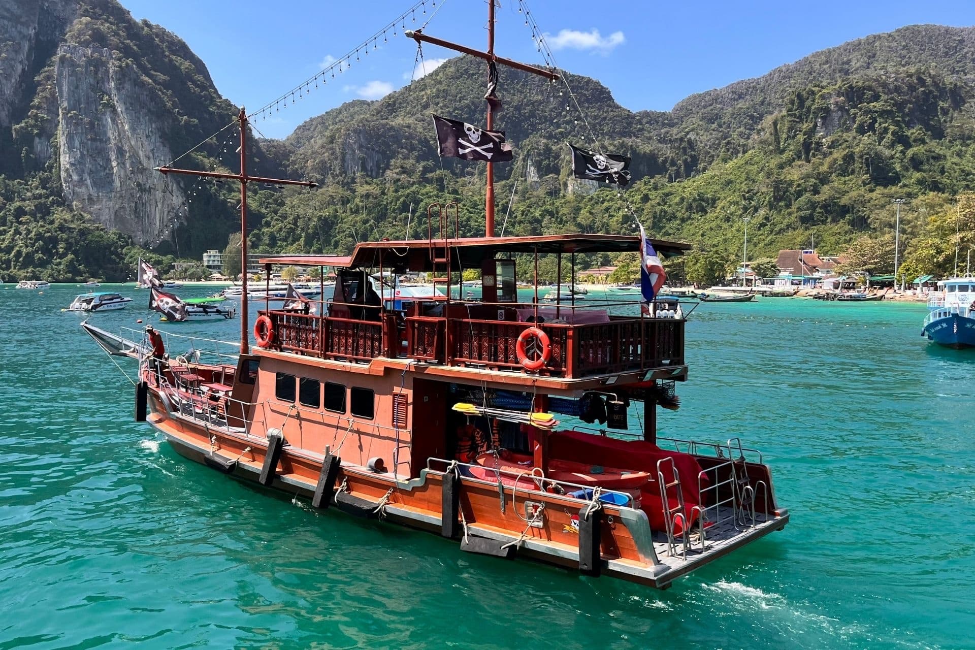 The Dragon — dark-hulled pirate galleon flying jolly rogers on the turquoise Andaman